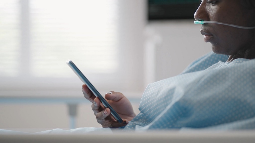 Hospital patient using a smartphone in bed, illustrating the use of translation apps during medical care abroad