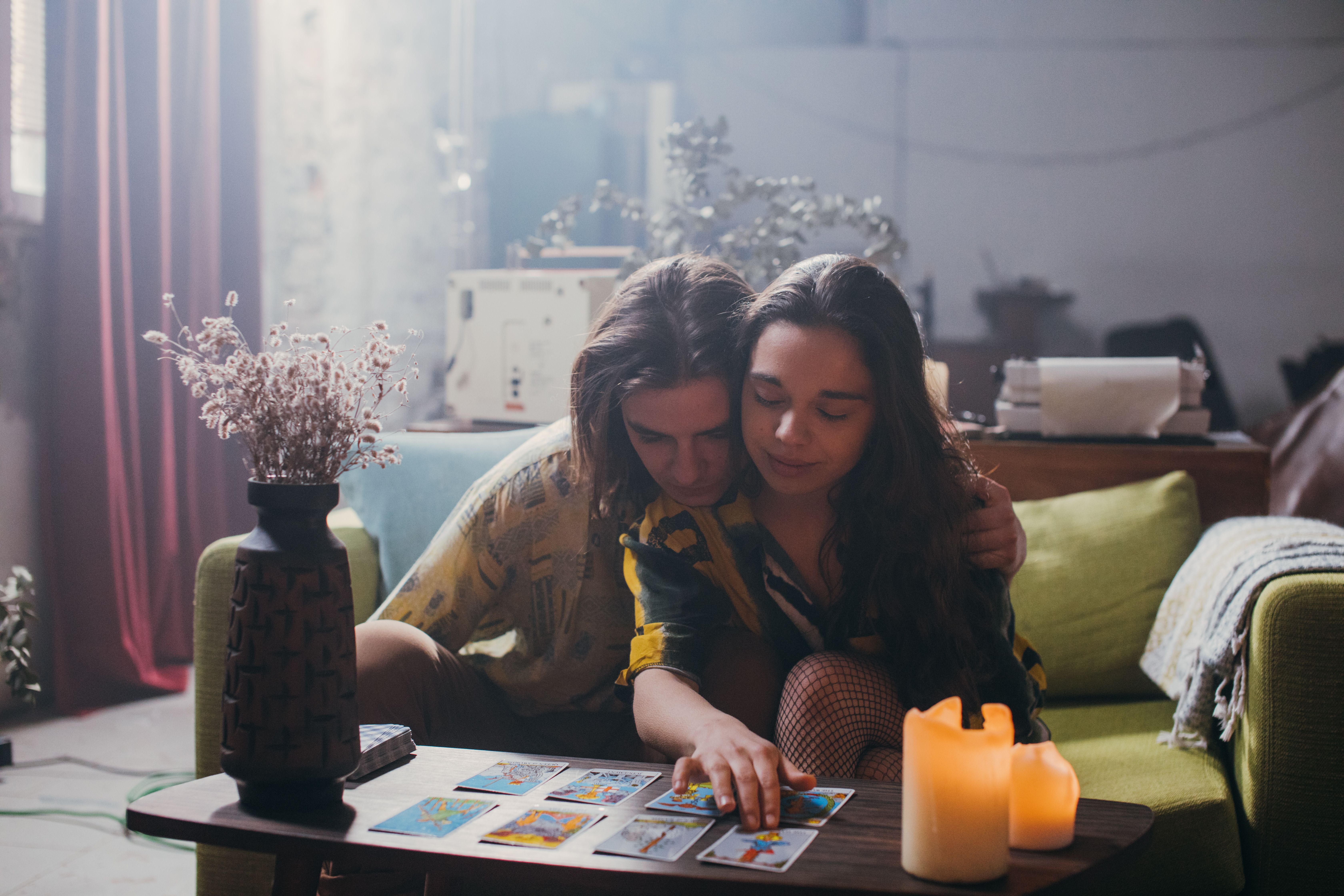 Couple exploring tarot cards together in a warmly lit room, bringing astrology and romance together.