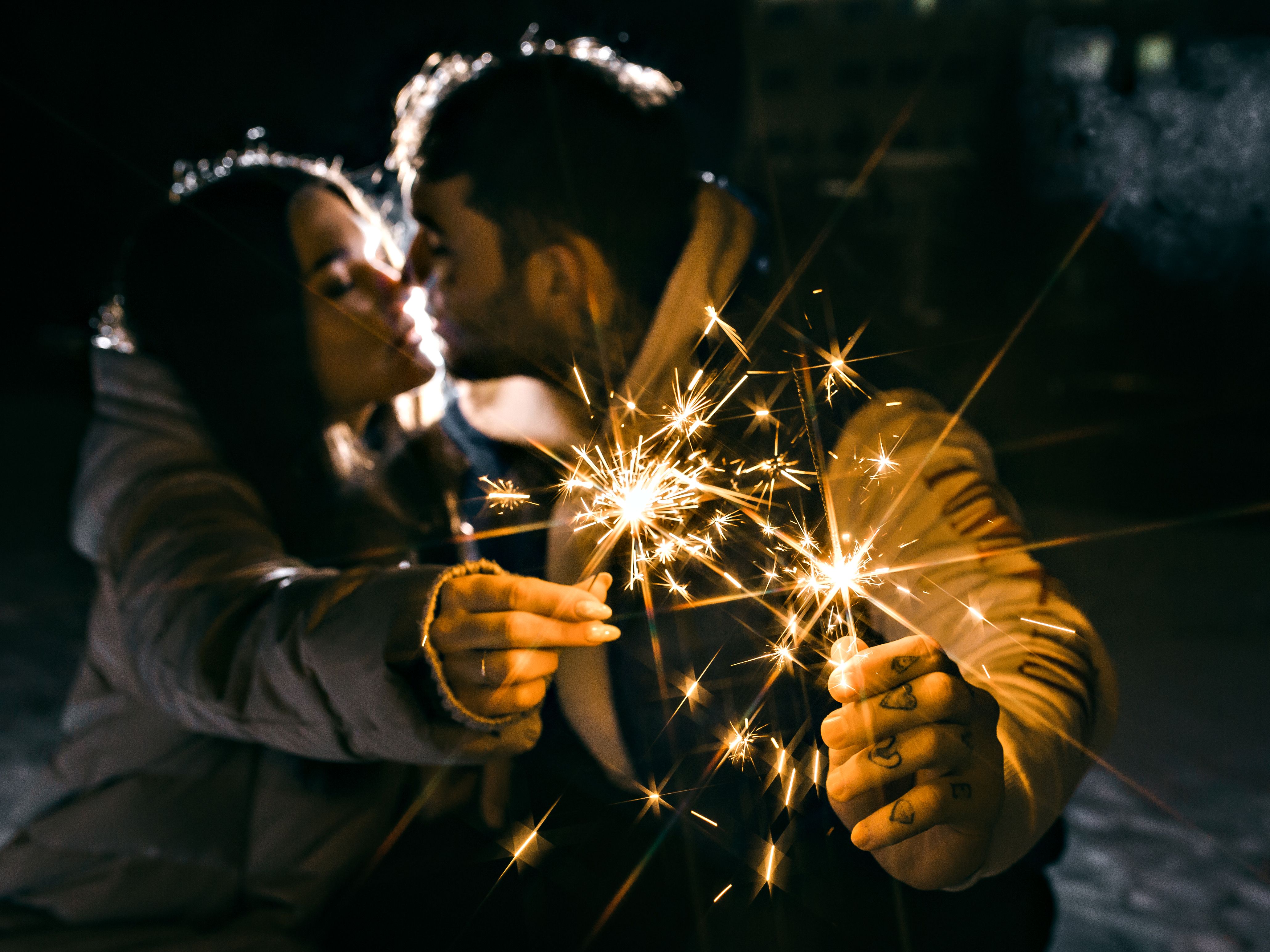 Couple sharing a kiss beside glowing sparklers, a vivid image of romantic chemistry and sparks.