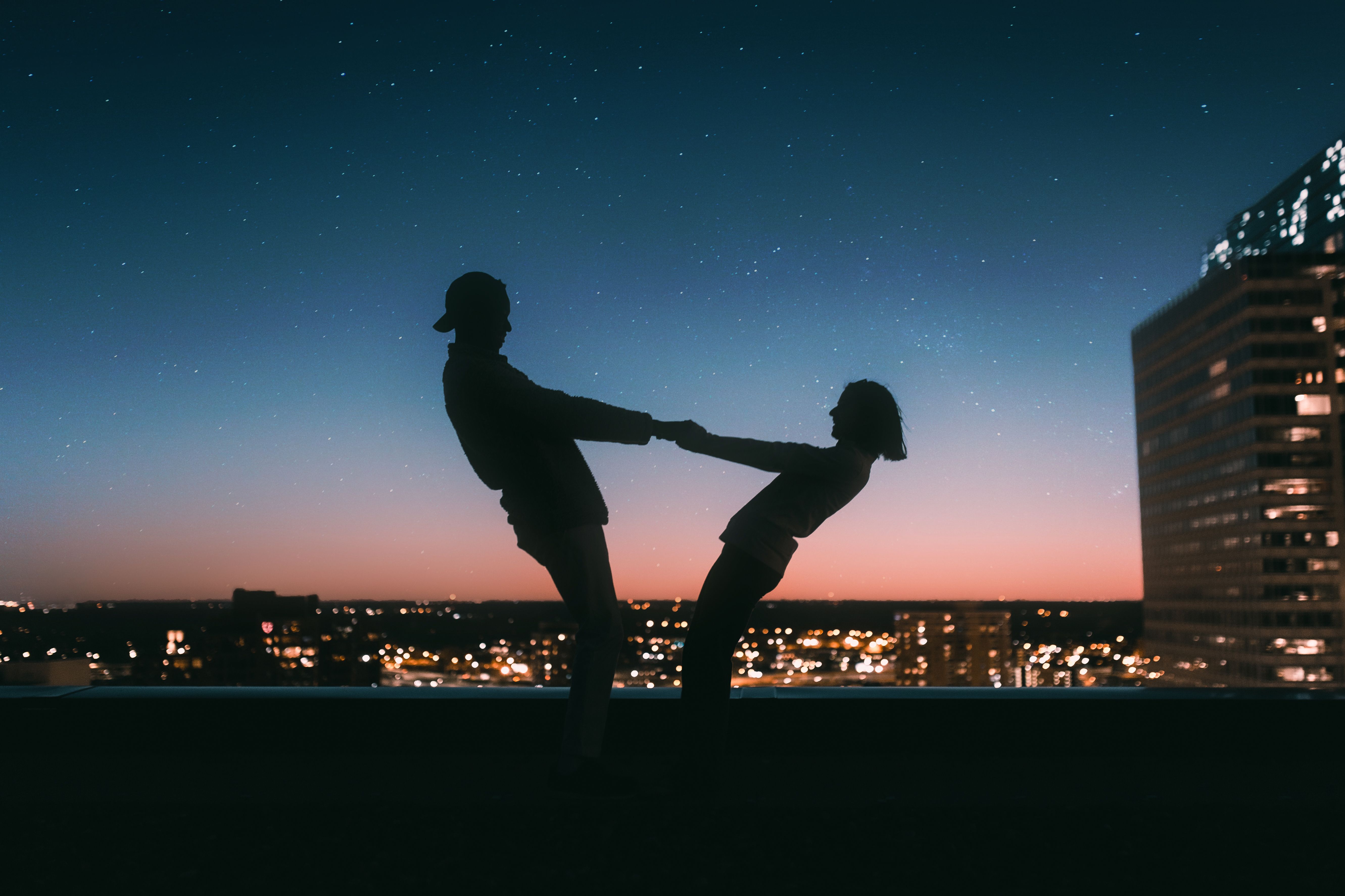 Couple silhouetted beneath a starry sky, evoking a celestial connection and astrological attraction.